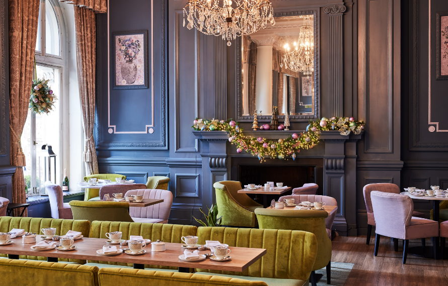 Elegant lounge with Christmas decor featuring green velvet chairs and a chandelier