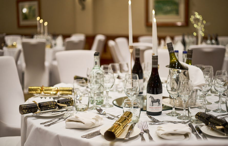 Elegant dining table set for Christmas with candles, wine bottles, and festive crackers