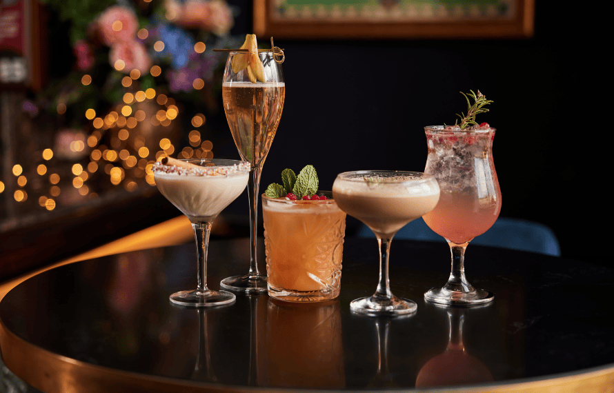 Assorted cocktails displayed on a table with a festive background
